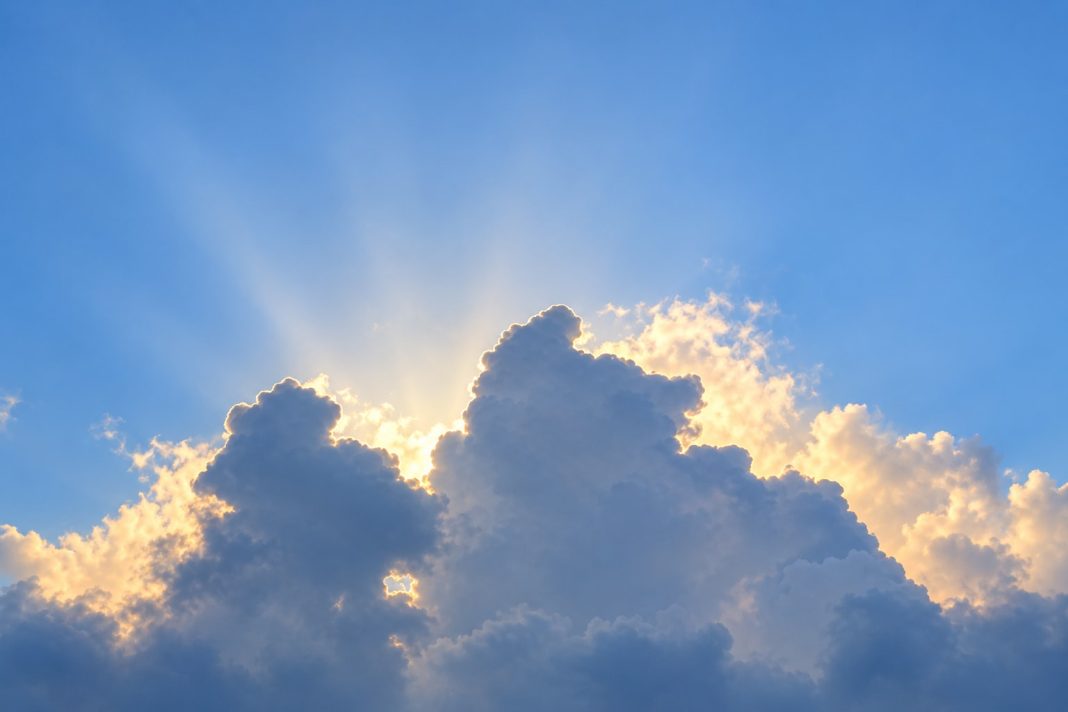 Sunlight edging billowing clouds beneath a blue sky
