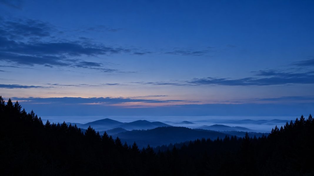 Layered hills and dark pine silhouettes beneath a natural blue twilight sky